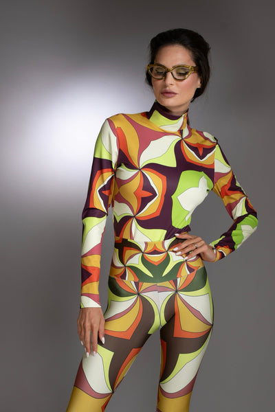 Person wearing a colorful bodysuit with a pattern and brown boots on a gray background