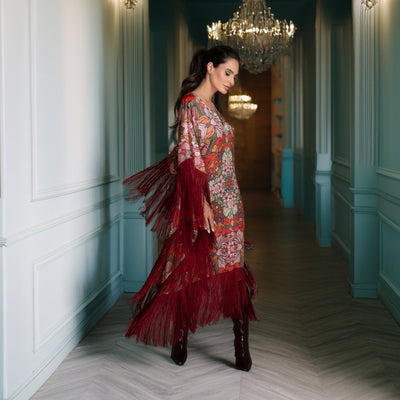 Woman in a colorful dress standing in an elegant hallway with decorative lighting.