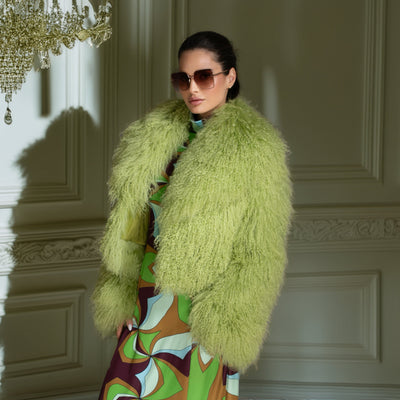 Woman wearing a bright green fur coat in an elegant interior setting