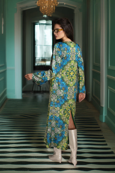 Woman in a floral dress walking down a stylishly decorated hallway with green walls and a black and white striped rug.