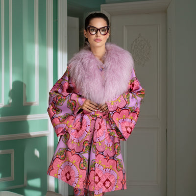 Woman in a pink robe with a floral pattern standing in a room with green walls.